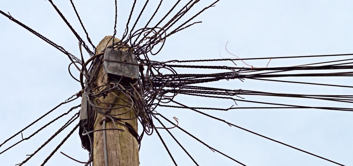 a mess of telephone wires on top of a telephone pole