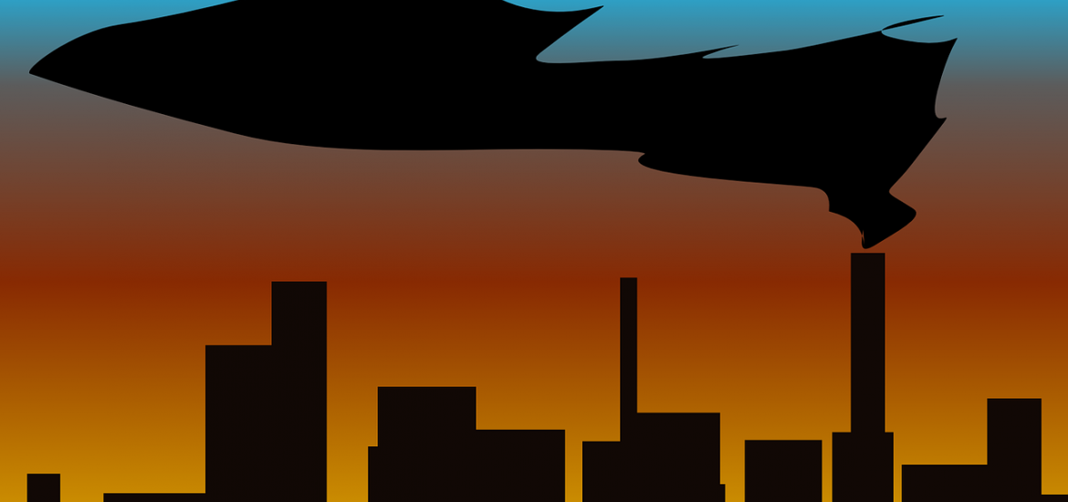 factories lined up against a sunset-colored sky. The sky is blue, orange, yellow.